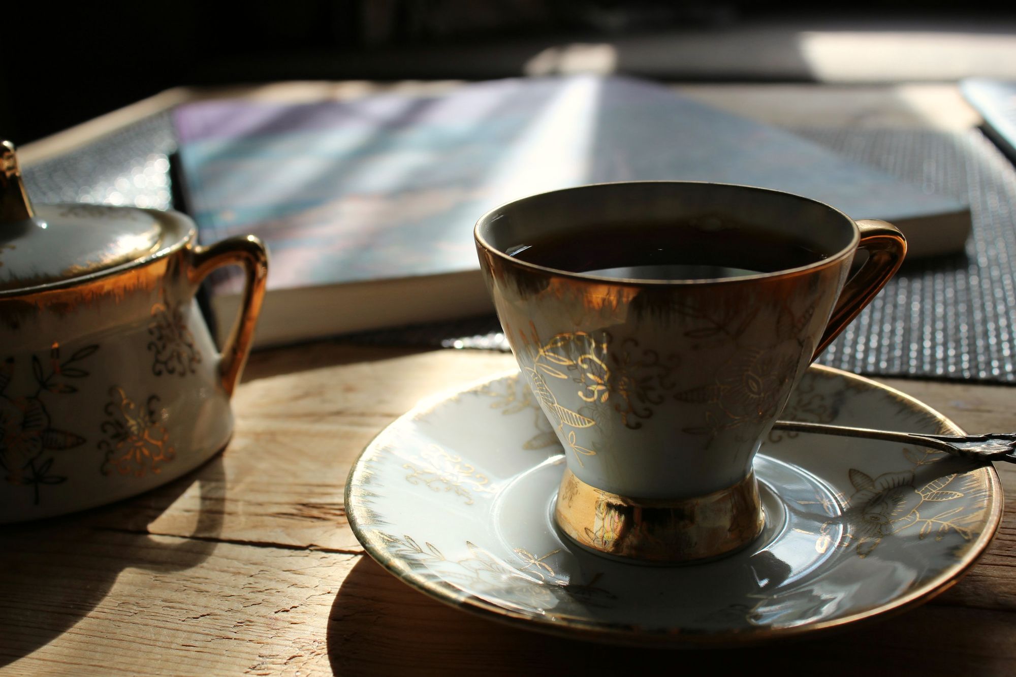 Una tazza di tè su un tavolo di legno, accanto a un libro